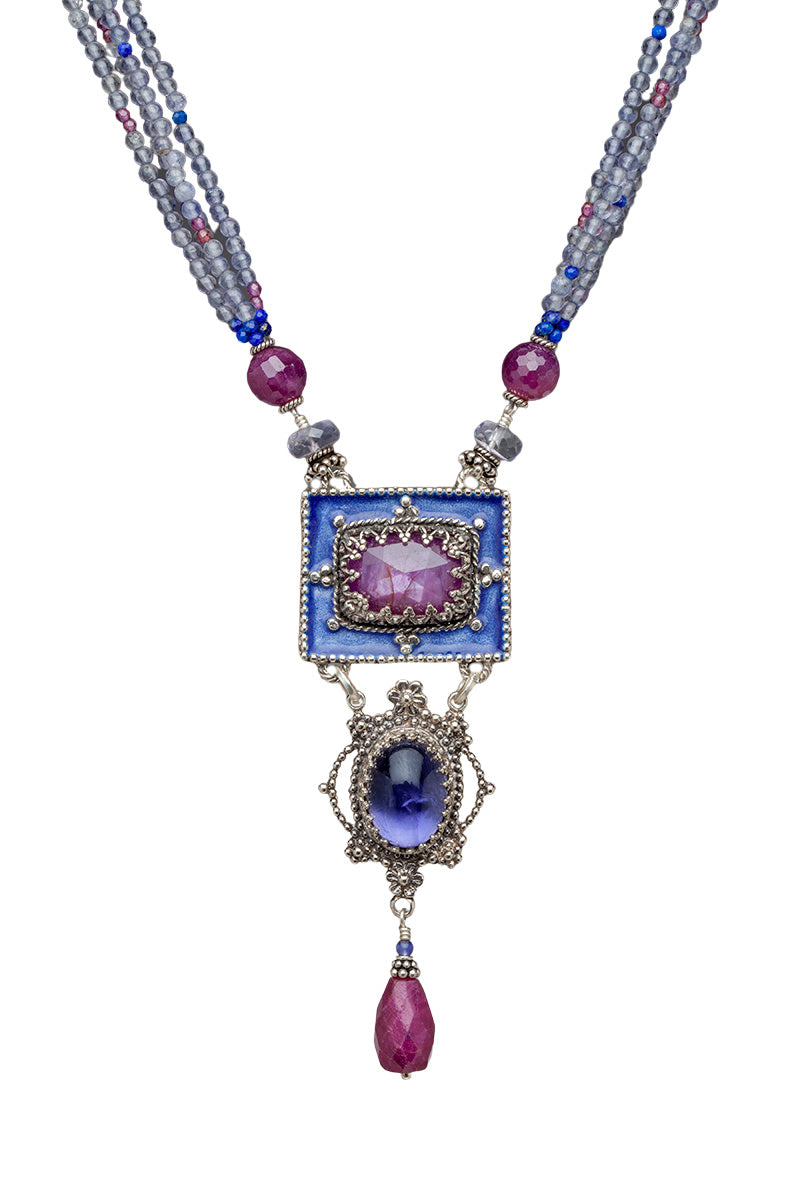 Gorgeous enameled pendant with a rectangular 14x10mm Pink Star Sapphire set in the center. From the main pendant hangs a pendant with an oval iolite set in a lacy bezel with small silver flower designs. From the bottom pendant hangs a beautiful Ruby drop. The necklace has 4 strands of 2mm Pink Amethyst, Lapis Lazuli & Rhodolite Garnet beads on each side.