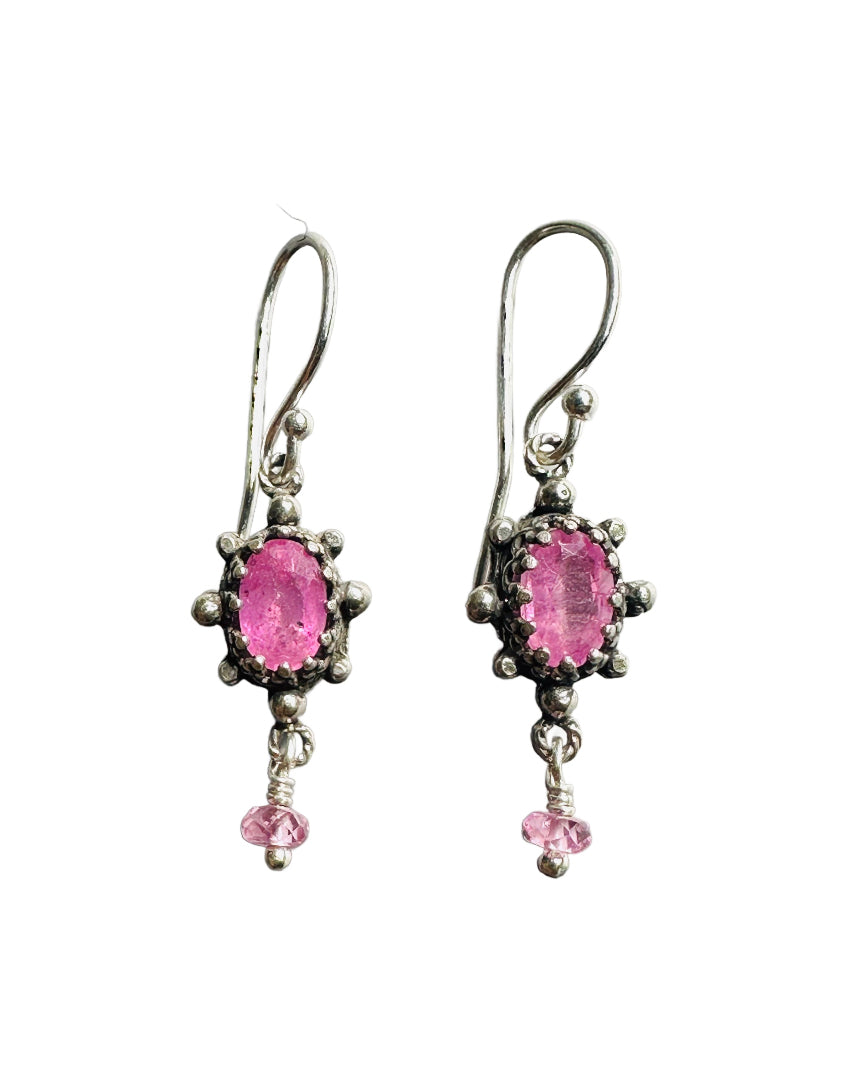 This super cute small earring features a beautiful faceted pink sapphire framed in a delicate, lacy bezel, with little silver dot accents. The stone setting has an open back to allow light to shine through and show the gem's beauty. From the vertical oval setting hangs a cut pink sapphire accent that gives the earring movement.&nbsp;