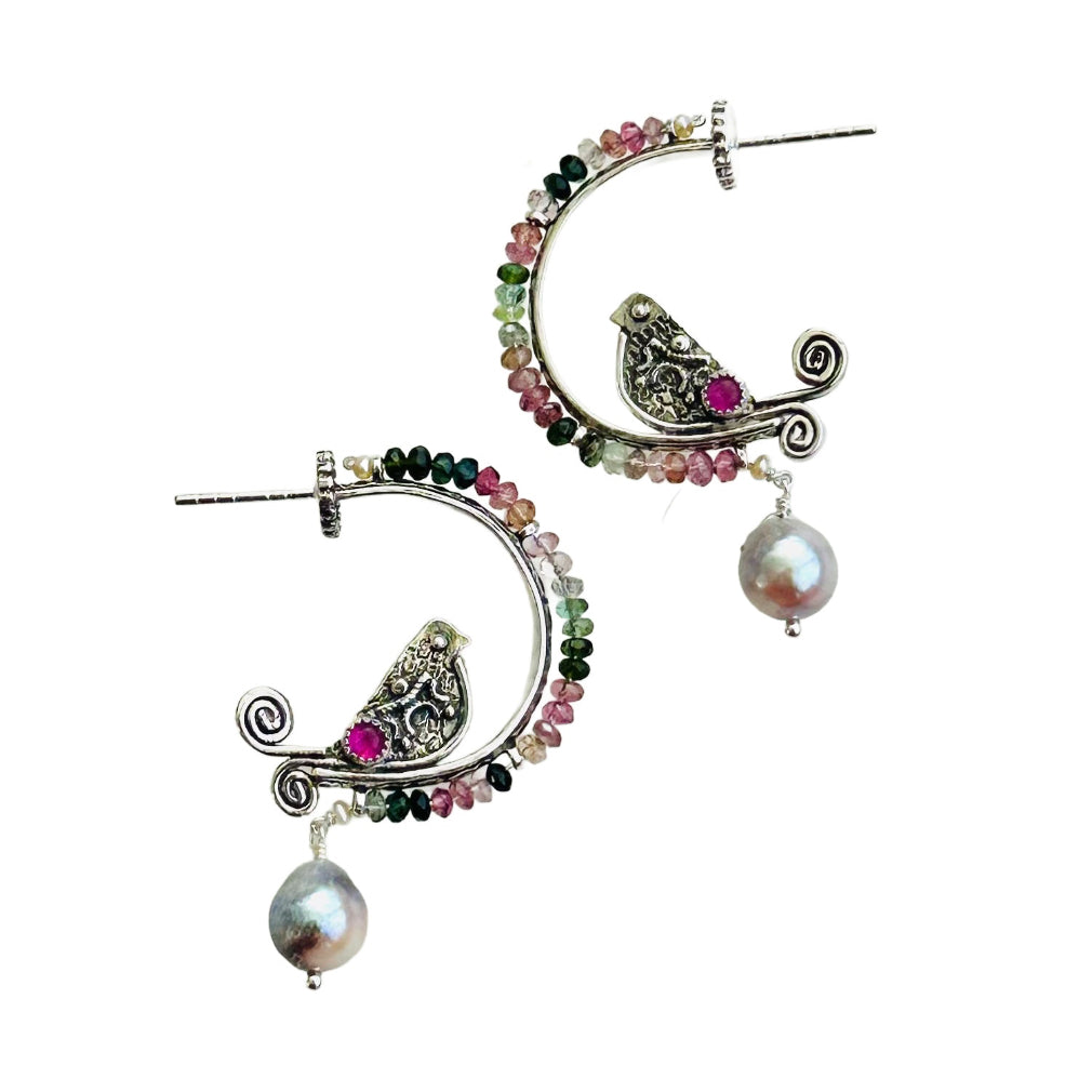 Tourmaline, Pink Sapphire & Pearl Beaded Silver Bird Hoops - Small

This is a whimsical, fun, and unique earring! The hoop itself has a beautiful floral pattern, the bird is engraved and has a detail wing and gem stone set on both sides. The hoop has a border of 2.5mm faceted multi colored tourmalines with a tiny pearl accent at either end, a cabochon pink sapphire gem is set in a silver bezel near the tail, and a beautiful silver pearl dangles from the bottom.