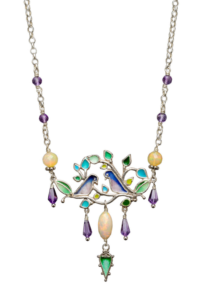Ethiopian Opal & Amethyst Love Bird Enameled Necklace

This beautiful and unique necklace features two birds on a tree branch. Birds and leaves are enameled and have multiple amethyst drops dangles and a main opal drop dangle in the center with an enameled leaf at the bottom.&nbsp;

Faceted Ethiopian Opals connect the main pendant to silver chain with small amethyst beads.

This necklace is 17" long and has an enameled flower clasp with a cabochon amethyst set in the center.

