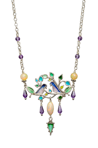 Ethiopian Opal & Amethyst Love Bird Enameled Necklace

This beautiful and unique necklace features two birds on a tree branch. Birds and leaves are enameled and have multiple amethyst drops dangles and a main opal drop dangle in the center with an enameled leaf at the bottom.&nbsp;

Faceted Ethiopian Opals connect the main pendant to silver chain with small amethyst beads.

This necklace is 17" long and has an enameled flower clasp with a cabochon amethyst set in the center.
