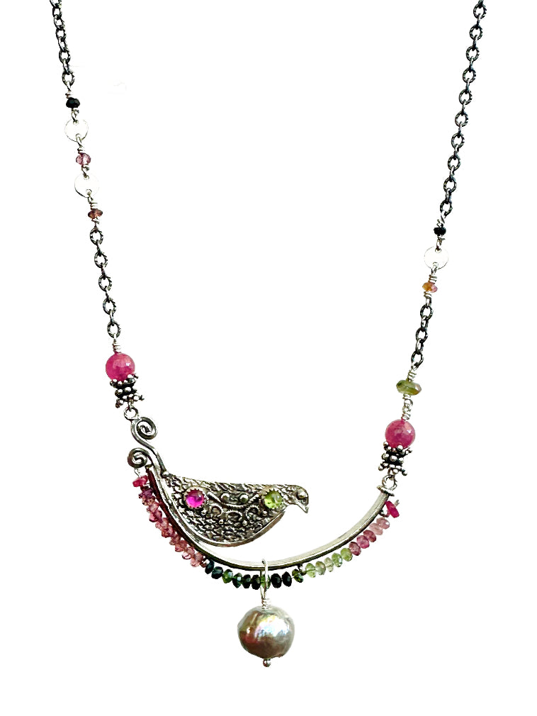 Tourmaline, Pink Sapphire & Pearl Beaded Bird Necklace - Silver

This is a whimsical, fun, and unique necklace!

The bird sits on a silver arch that has a beautiful floral pattern. The bird is engraved and has a detail wing on both sides. On the front side of the bird, there are two gems set. The silver arch has a border of 2.5mm faceted multi colored tourmalines with a & pink sapphire accent at either end, a cabochon pink sapphire and green tourmaline gems are set in a silver bezel near the tail an