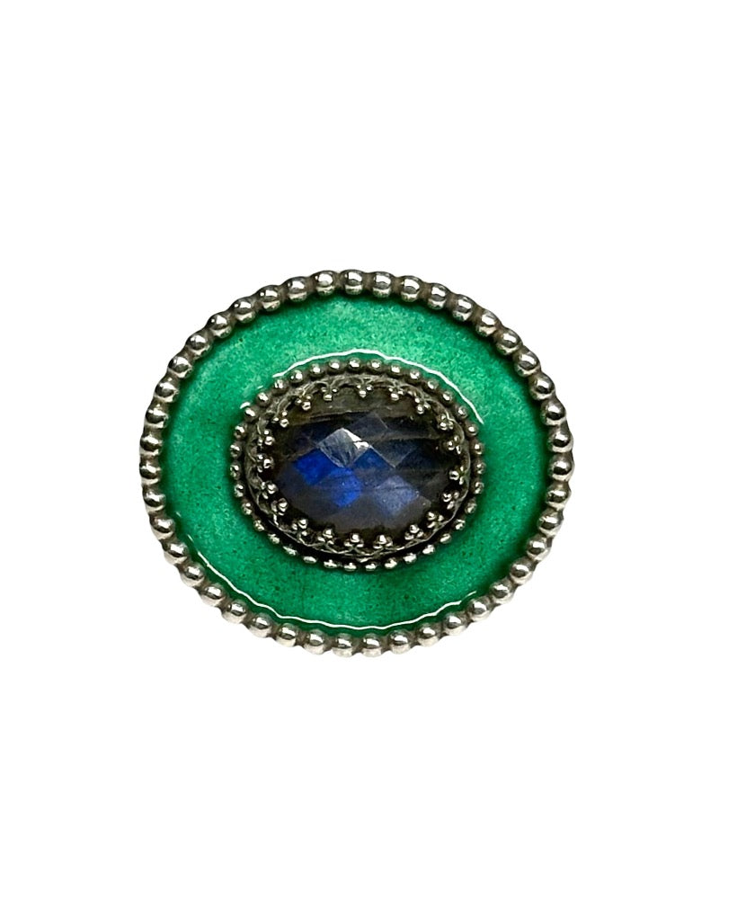 A horizontal 1"x7/8" oval with a teal green enamel,  has a 11x9mm rose cut labradorite set in the center, in a lacy bezel. The band has a delicate floral pattern, is 1/8" and sturdy.    This ring is a size 6.5