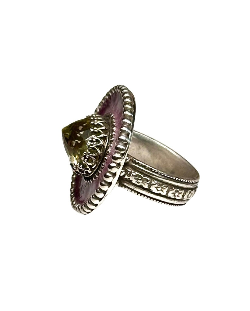 A horizontal 1"x7/8" oval with a pink enamel with a burgundy border,  has a 11x9mm beautifully cut lemon citrine set in the center, in a lacy bezel. The band has a delicate floral pattern, is 1/8" and sturdy.    This ring is a size 6.5  Materials: Sterling silver, enamel & lemon citrine