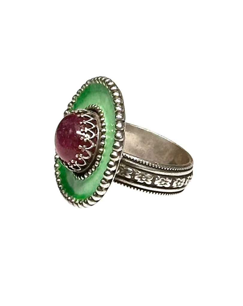 A horizontal 1"x7/8" oval with a light green with a darker green border enamel,  has a 11x9mm beautiful cabochon pink tourmaline set in the center, in a lacy bezel. The band has a delicate floral pattern, is 1/8" and sturdy.    This ring is a size 8.5  Materials: Sterling silver, enamel & pink tourmaline  This ring is unique, fun, beautiful and colorful!    