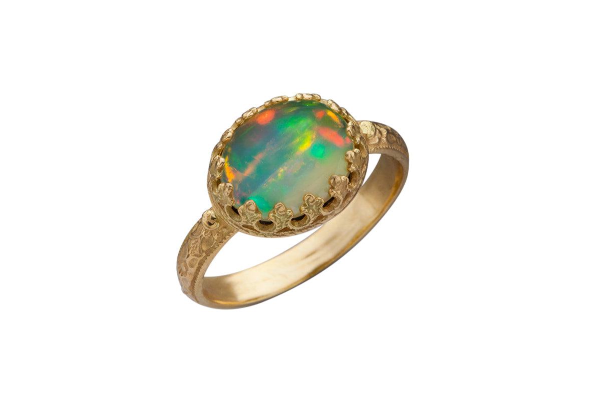 This 18K recycled gold with beautiful cabochon 10x8mm oval Ethiopian Opal ring is gorgeous, such a rich color combo! The Ethiopian Opal is set in a delicate filigree bezel, that showcases the stone beautifully. The shank has a lovely pattern, and has a gold dot on either side of the stone. 