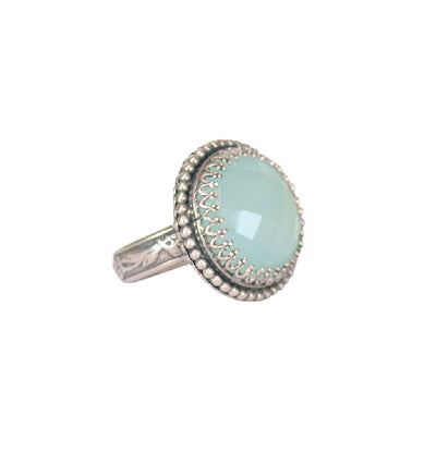 Round Aqua Chalcedony Cocktail Silver Ring Media 1 of 2       RoundAquaChalcedonyCocktailSilverRing 791 × 1000px Aqua Chalcedony Cocktail Ring This is such a fun, and elegant ring! A beautifully 16mm rose cut aqua chalcedony is set in a filigree bezel, and surrounded by a strand of tiny silver dots. The shank has a beautiful botanical pattern. Perfect with jeans or a gown. Ring available in size 7, 7.5, 8.75 & 9.5 Materials: Sterling silver & aqua chalcedony  Edit alt text